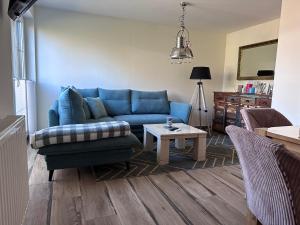 a living room with a blue couch and a table at Karolina‘s Deluxe Appartement-Bungalow in Dranske