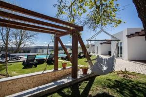 a swing in a yard with a pool at Charming House with Pool in Atalaia in Lourinhã