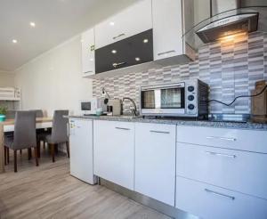 a kitchen with white cabinets and a table with a microwave at Charming House with Pool in Atalaia in Lourinhã