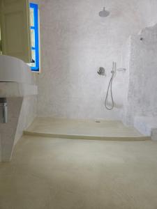 a white bathroom with a shower and a sink at Phaos Oia Suites in Oia +30 photos