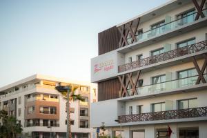 a building with a palm tree in front of it at Zephyr Agadir in Agadir