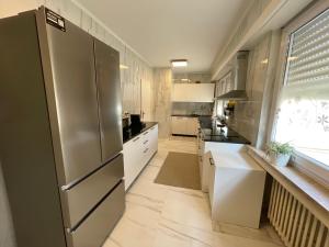 una cucina con frigorifero in acciaio inossidabile e armadietti bianchi di 暖暖屋 a Mamer