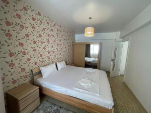 a small bedroom with a bed with white sheets and floral wallpaper at Sunny Central Apartments Zamca in Suceava