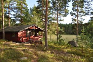 una cabaña en el bosque con un banco y una mesa en Hinders Cottages en Nauvo