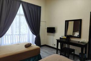 a bedroom with a bed and a desk and a mirror at Terengganu Equestrian Resort in Kuala Terengganu