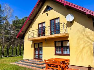 a yellow house with a bench in front of it at Między Świerkami in Krasnobród