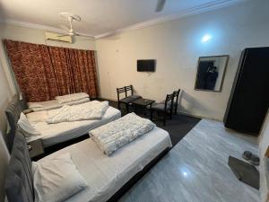 a room with two beds and a table and a television at Grand Arham Hotel in Dargai