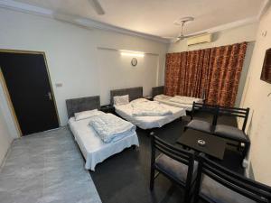 a room with three beds and a table and chairs at Grand Arham Hotel in Dargai +32 photos
