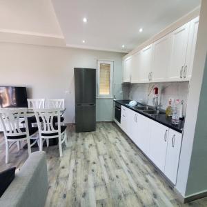 a kitchen with white cabinets and a black refrigerator at Urban Charm Lalzi in Draç