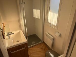 a small bathroom with a sink and a shower at Mobil home camping kerlann 6 personnes 2 chambres emplacement idyllique in Pont-Aven +7 photos