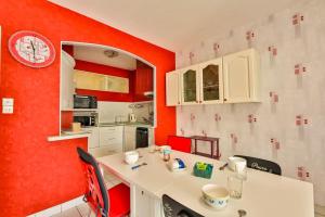 a kitchen with red walls and a white table and chairs at Valentin - 50m plage - Parking in Plage-des-Demoiselles