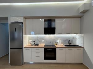 a kitchen with white cabinets and a stainless steel refrigerator at Elysium residence Apartment in Nydri