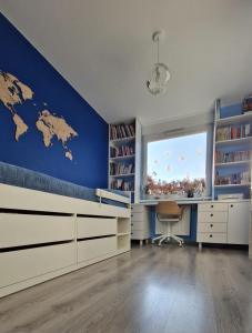 a bedroom with a blue wall with a bed and a window at Osiedle Morskie in Pogórze