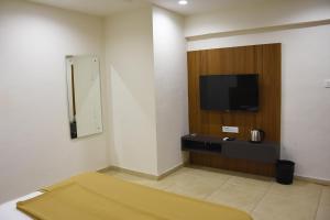 a room with a flat screen tv on a wall at Prince Residency in Jamnagar