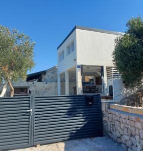 a white house with a gate in front of it at Holiday house with a parking space Drvenik , Drvenik - 24088 in Dolići
