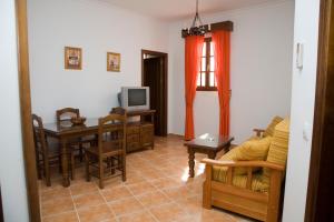 ein Wohnzimmer mit einem Sofa, einem Tisch und einem TV in der Unterkunft Apartamentos Reysan in Vejer de la Frontera