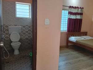bagno con servizi igienici, letto e finestra di MM comforts a Mysore