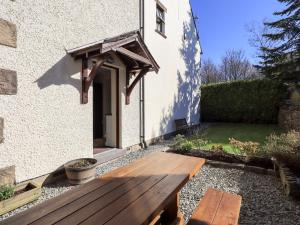 un banco de madera sentado fuera de una casa en Ramshead Cottage, en Penrith