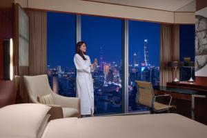 a woman standing in front of a window in a hotel room at Shanghai Marriott Marquis City Centre in Shanghai