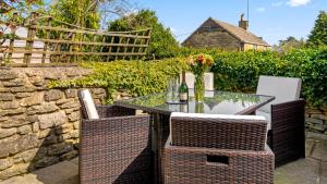 un patio con tavolo in vetro e sedie di Horsefair Cottage a Malmesbury