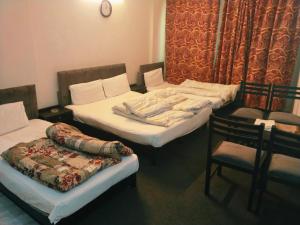 a room with two twin beds and a chair at Grand Arham Hotel in Dargai