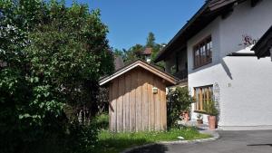 a small wooden shed next to a white building at Ferienwohnungen Kaiser Franz in Krün