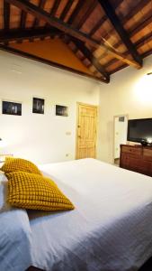 a bedroom with a white bed with a yellow pillow at LA ALDABA, antigua casa de labor in Almagro +56 photos