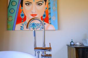 a sink in a bathroom with a painting on the wall at Hillside Chalet with panoramic views in Amed