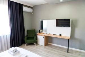 a hotel room with a desk and a green chair at Rio's Hotel AİRPORT in Istanbul
