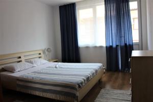 a bedroom with a bed with blue curtains and a window at Апартаменти Амфора in Pomorie