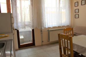a kitchen with a table and a refrigerator and windows at Апартаменти Амфора in Pomorie