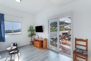 a living room with white walls and a sliding glass door at Los Adejo vacacional in Moya