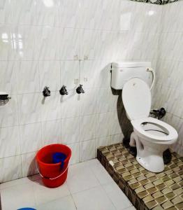 a bathroom with a toilet and a red bucket at Sunlight Homestay Mohana in Chakrāta