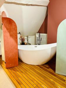 a bathroom with a white tub on a wooden floor at La Maitrise à BAYEUX in Bayeux +20 photos