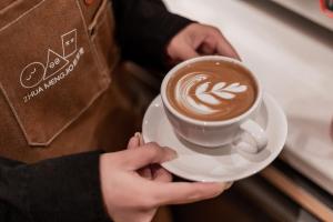 a person holding a cup of coffee on aucer at Cheens Hotel in Chengdu