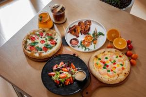 two pizzas on a wooden table with plates of food at Cheens Hotel in Chengdu