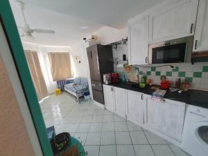 una cucina con armadi bianchi e pavimenti piastrellati bianchi e verdi. di Casa al mare Sardegna a Isola Rossa