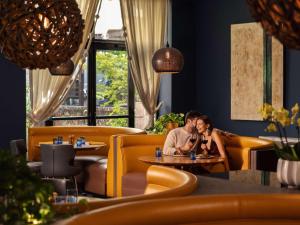 a man and woman sitting at a table in a restaurant at Hotel Sofitel Los Angeles at Beverly Hills in Los Angeles