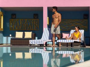 a man and a woman standing next to a swimming pool at Hotel Sofitel Los Angeles at Beverly Hills in Los Angeles