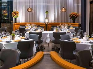 a dining room with white tables and chairs at Hotel Sofitel Los Angeles at Beverly Hills in Los Angeles