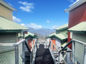 a walkway between two buildings with mountains in the background at Huski Ski Club in Mount Buller