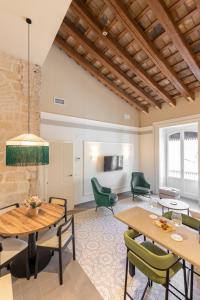 a living room with wooden tables and green chairs at Aladro Apartamentos by Valcambre in Jerez de la Frontera