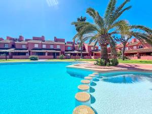 a swimming pool with a palm tree and a building at Albatros Playa 2 - 5810 in Mar de Cristal