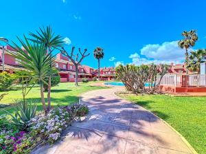 a walkway through a park with palm trees and flowers at Albatros Playa 2 - 5810 in Mar de Cristal