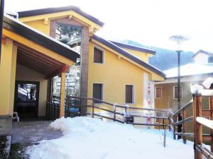 a yellow house with snow in front of it at Residence Acero Rosso in Ponte di Legno