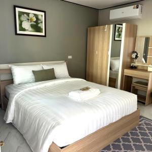 a bedroom with a large white bed with a mirror at MBB House in Thalang