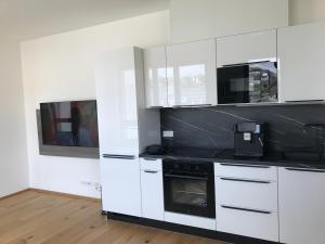 a kitchen with white cabinets and black appliances at Apartmantplus01 in Prague