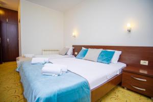 a bedroom with two beds with blue and white pillows at Hotel Odissey Jaz in Budva