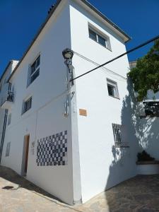 a white building with a black and white checkered at Casa La Paz in Genalguacil