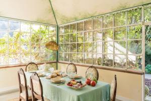 a table with a bowl of fruit on it in a room with windows at Relais La Foleia - Luxury Villa with private lake in Veruno